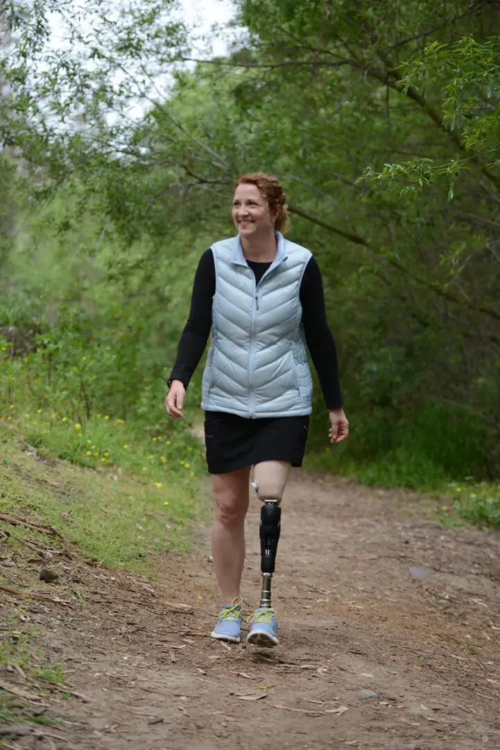 A woman walking down the road with a leg cast on her right foot.