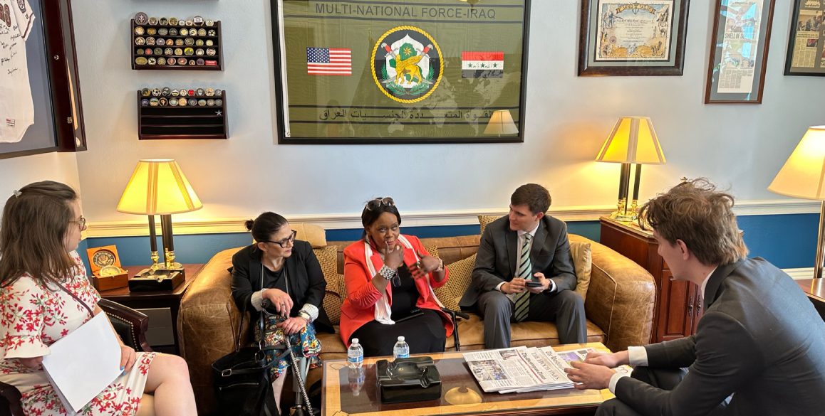 Three people sitting on a couch in front of a wall.