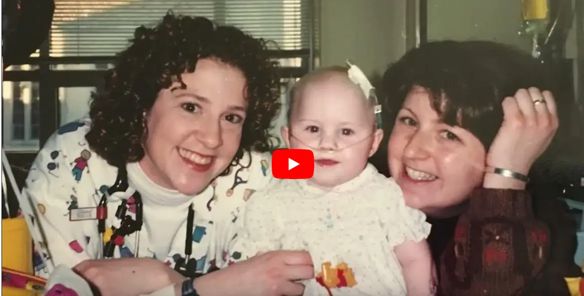 A woman holding a baby and another woman smiling.